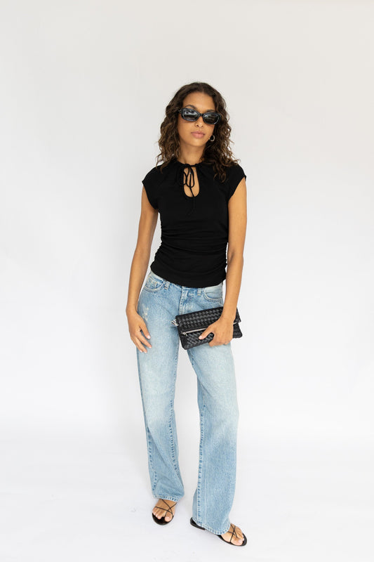 Woman wearing a black top and light blue jeans on a white background